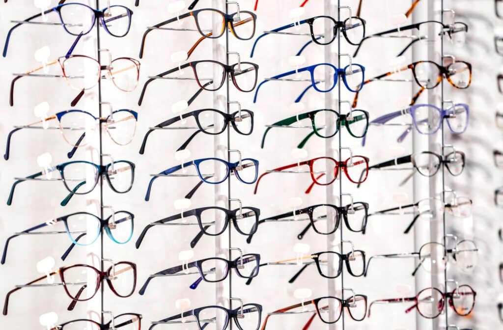 Display of assorted eyeglass frames in various colours and styles arranged neatly on a rack in an optical store.