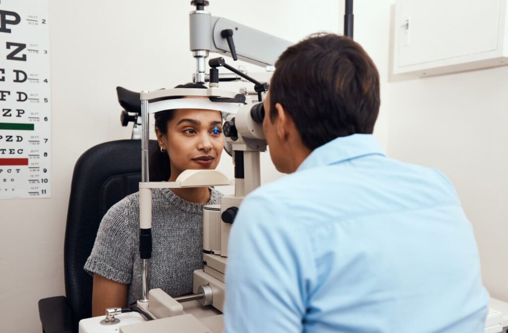 Optometrist performing an eye exam on a woman using a slit lamp