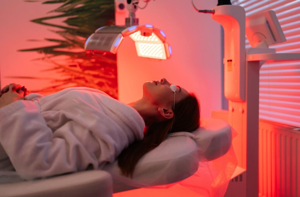 Someone laying on a table with protective eye wear on while doing red light therapy.