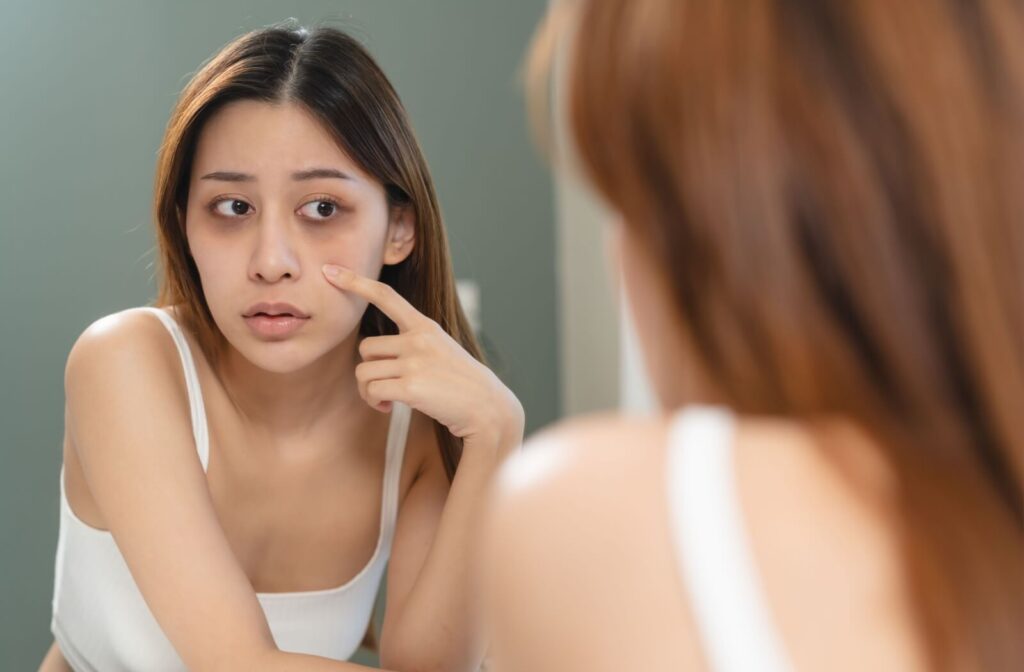 Someone looking into the mirror with dark under eye circles.