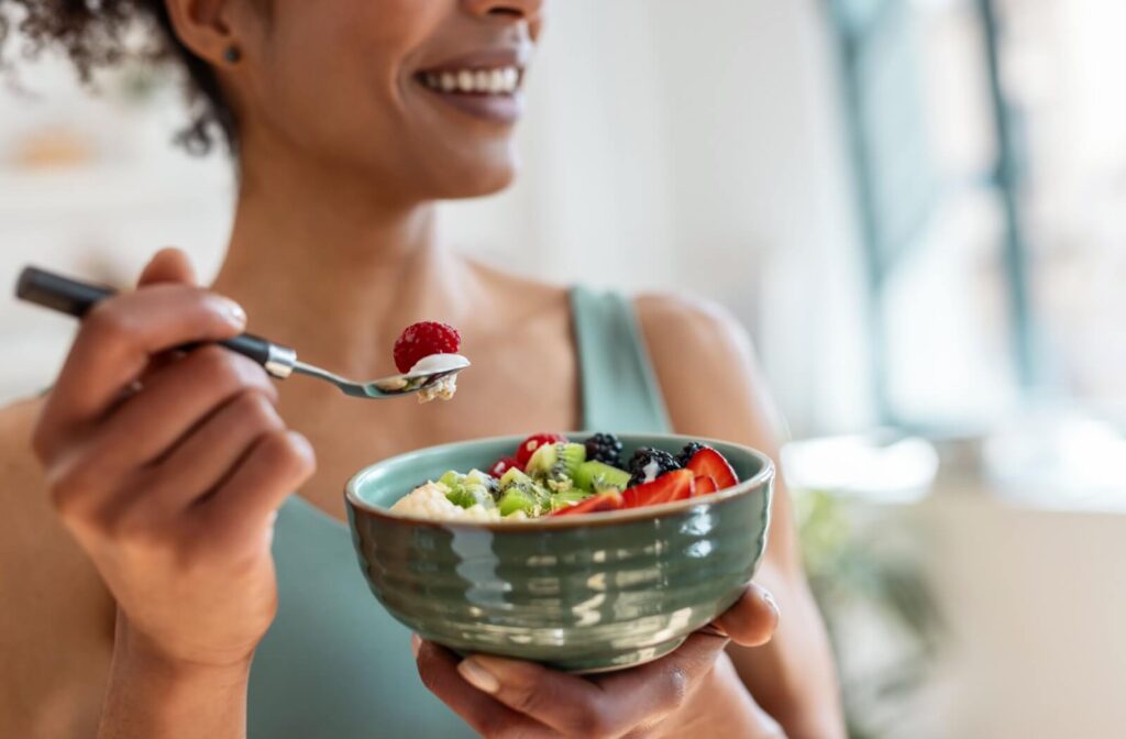 An adult eating a bow of nutritious fruits.